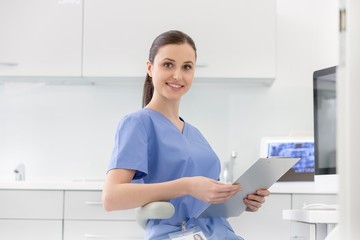 Attractive nurse sitting while holding medical record in clinic