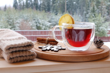 Wall Mural - The glass mug of hot tea on the winter forest background. 