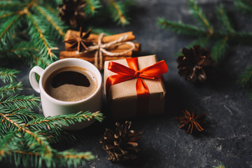 christmas background with tree branches, coffee and gift box on dark stone table