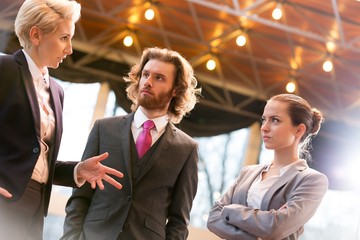 Wall Mural - Tilt shot of mature businesswoman discussing with colleagues while standing at office