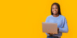 © Prostock-studio - Cheerful black girl holding laptop over yellow background