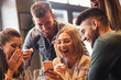 © Zoran Zeremski - Group of young friends having fun in restaurant talking, laughing while dining at table and making selfie.