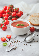 White Bowl Plate Of Creamy Tomato Soup With Spoon On Light Table Background With Box Of Raw Tomatoes And Bread.
