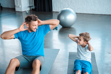 Poster - cute kid and father exercising on fitness mats and looking at each other