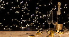 New Year's Eve Background With Champagne Bottle And Glasses Confetti And Gold Snakes New Year's Eve Background With Confetti And Gold Snakes On Wooden Table, Lights