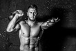 © Srdjan - Young strong sweaty focused fit muscular man with big muscles holding heavy kettle bell for cross training hard core workout in the gym black and white