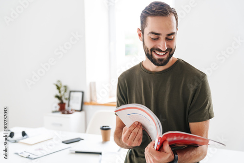 Cuadros en Lienzo Image of caucasian happy man reading brochure and smiling
