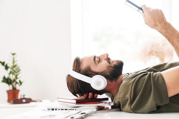 Canvas Print - Image of man listening music with headphones and using cellphone