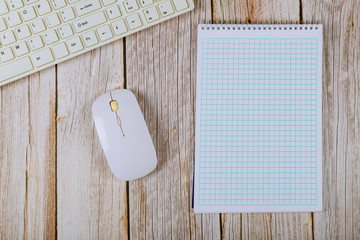 Office table with blank notebook and keyboard on a wooden table background.