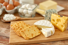 Food And Eating Concept - Close Up Of Salty Crackers And Cheese On Wooden Board