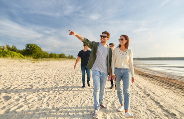 Canvas Print - friendship, leisure and people concept - group of happy friends walking along beach in summer