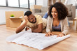 mortgage, people and real estate concept - happy african american couple with boxes and blueprint moving to new home