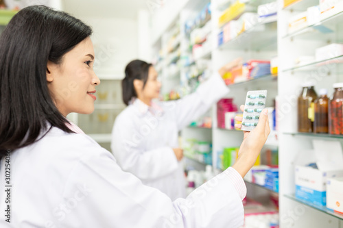 Cuadros en Lienzo asian female pharmacist check medicine stock in drugstore,she holding drug strip