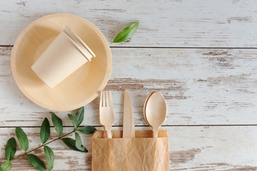 Eco friendly disposable dishes made of bamboo wood and paper on white wooden background.