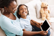 © Prostock-studio - African-american mom and daughter using digital tablet