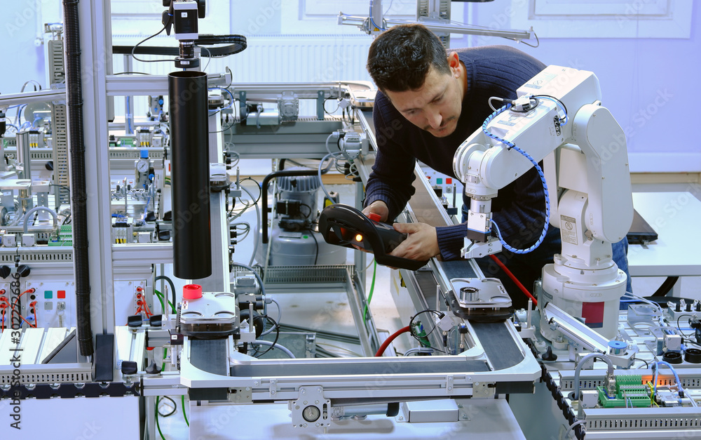 Man is programming robot arm with control panel which is integrated on ...