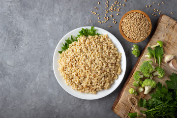 Canvas Print - Boiled spelt on a plate. Healthy food. Gray concrete background. Top view with copy space.