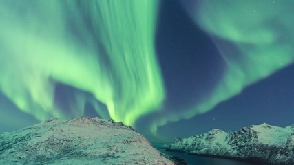 incredible northern lights display over a fjord in arctic northern norway.
