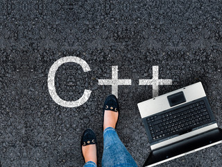 c++ programming language. .a woman steps to a laptop and c++ on asphalt road