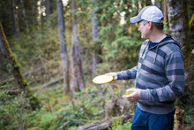 Man Prepares To Throw Frisbee During A Disk Gold Game In The Forest.