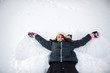 © Cavan Images - Girl smiling while making snow angel in the snow in front yard