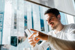 © Cavan Images - Smiling young man working in a cafe looking at cell phone