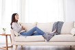 © Blue Jean Images - Happy young Chinese woman reading book on sofa