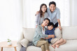 © Blue Jean Images - Happy Chinese family relaxing on sofa