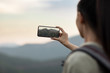 © Blue Jean Images - Young Chinese woman taking photos with smartphone outdoors