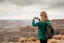 Side View Of Woman In Jacket With Backpack Photographing Pictorial View Of Canyon In USA