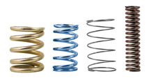 Four Steel Compression Coil Springs With Varied Surface Finish Isolated On White Background. Springy Metallic Machine Parts. Set Of Different Flexible Elastic Shock Absorbers With Spiral Wire Winding.