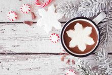 Hot Chocolate With Snowflake Marshmallow. Top View Corner Border With Snowy Branches And Candy Against A White Wood Background With Copy Space.