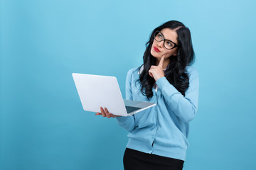 Wall Mural - Young woman with a laptop computer in a thoughtful pose on a blue background