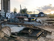 © Aliaksandra - Inside view of a large industrial construction site behind a fence with tools, barrel pipes and building materials on which new houses are being built