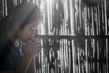 Girl while praying for christian religion with blurred of her body background.