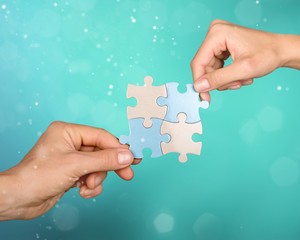 Poster - Human hands joining puzzle parts on blurred background