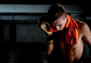 Muscular man with boxing gloves taking break from exercise