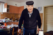 © Miljan Živković - Senior man grandfather old pensioner farmer wearing black sweater and hat having a cup of coffee or tea cooking in the pot at home waiting to boil