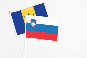 Slovenia and Barbados stick flags on white background. High quality fabric, miniature national flag. Peaceful global concept.White floor for copy space.