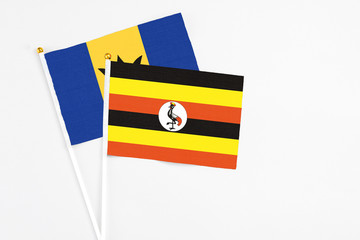 Uganda and Barbados stick flags on white background. High quality fabric, miniature national flag. Peaceful global concept.White floor for copy space.