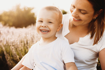 Wall Mural - poritrao f a beautiful mother looking at her little sun while playing in field of flowers. little ki