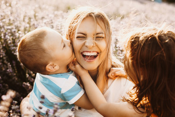 close up portrait of a lovely young mother laughing while playing with her kids while her son is kis