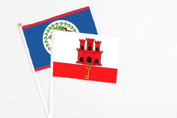 Gibraltar and Belize stick flags on white background. High quality fabric, miniature national flag. Peaceful global concept.White floor for copy space.