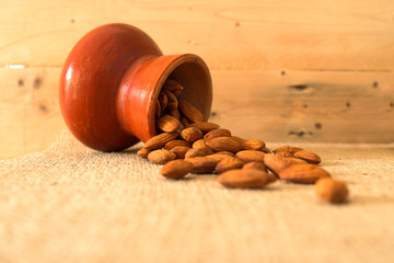 Almond nuts in earthenware on sackcloth with wooden background