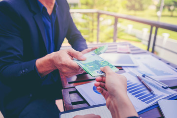 Wall Mural - Businessman giving EURO money to partner for business investment on the table