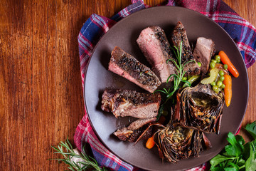 Canvas Print - Slices of beef steak served with baked artichoke