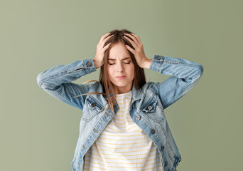 Wall Mural - Young woman suffering from headache on color background