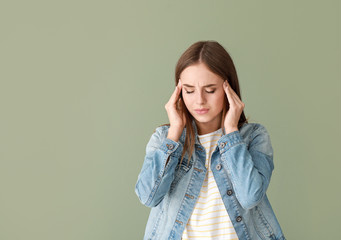 Wall Mural - Young woman suffering from headache on color background