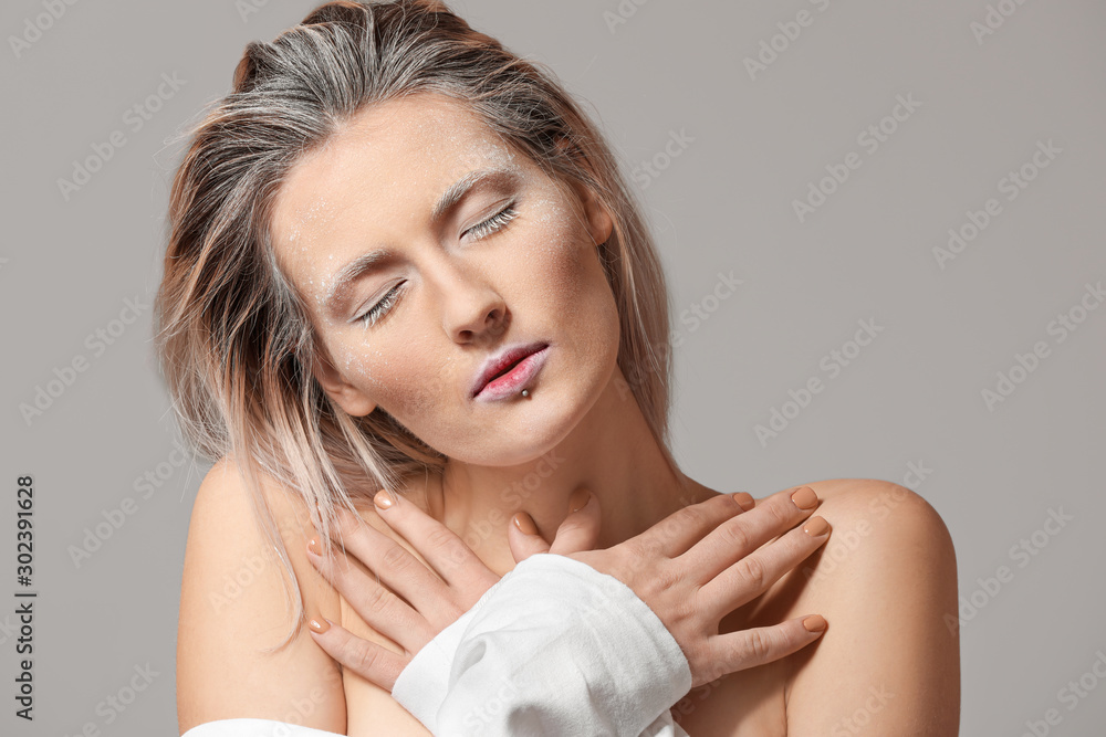 Beautiful woman with creative makeup on grey background