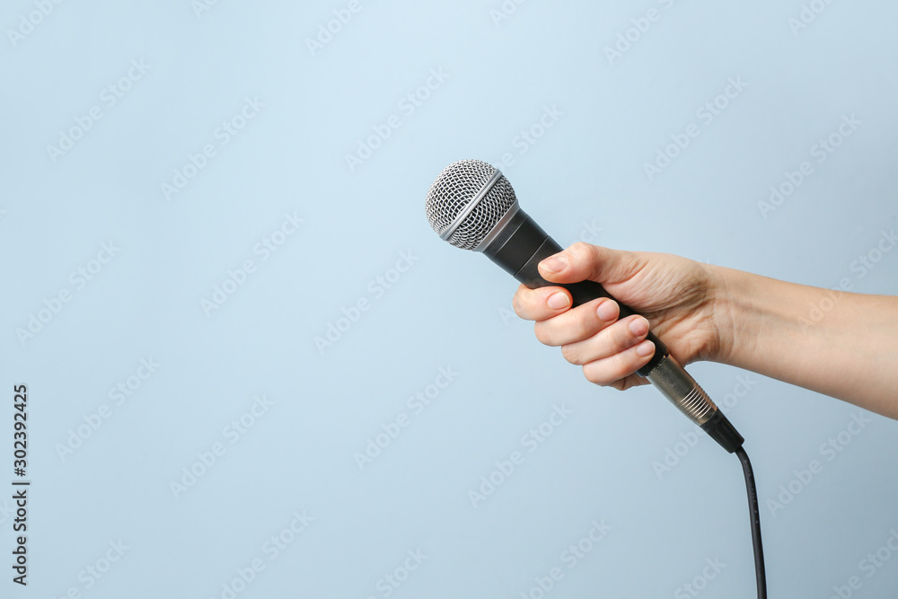 Female hand with microphone on color background - obrazy, fototapety, plakaty 